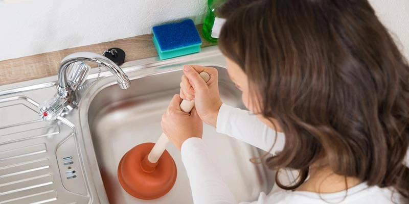 Person using a plunger on a clogged drain